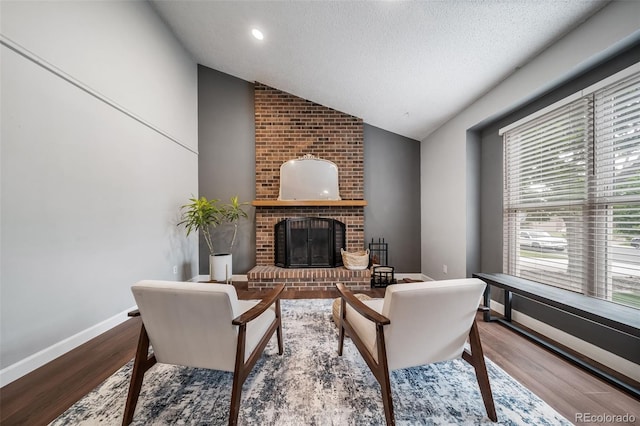 17372 E Prentice Cir, Centennial, CO 80015 - living area with vaulted ceiling, wood finished floors, a brick fireplace, baseboards, and a textured ceiling