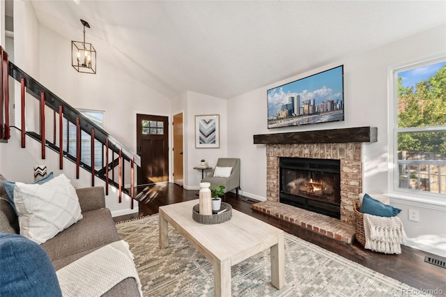 517 Chiswick Cir, Highlands Ranch, CO 80126 - living room with wood finished floors, lofted ceiling, stairway, a brick fireplace, and a chandelier