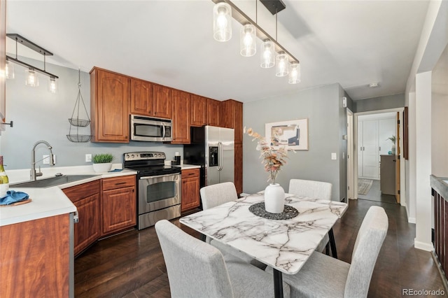 517 Chiswick Cir, Highlands Ranch, CO 80126 - kitchen featuring stainless steel appliances, brown cabinets, light countertops, dark wood-style floors, and decorative light fixtures