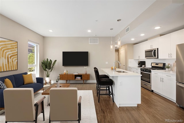 2374 S University Blvd Unit 202, Denver, CO 80210 - kitchen with stainless steel appliances, a sink, open floor plan, dark wood-style flooring, and a kitchen bar