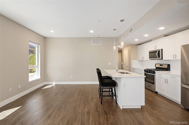 2374 S University Blvd Unit 202, Denver, CO 80210 - kitchen featuring stainless steel appliances, a sink, a kitchen breakfast bar, dark wood finished floors, and a kitchen island with sink