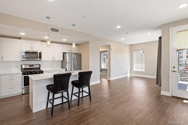 2374 S University Blvd Unit 202, Denver, CO 80210 - kitchen with appliances with stainless steel finishes, light countertops, a center island with sink, backsplash, and a breakfast bar