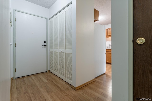 hallway featuring light wood-type flooring and a textured ceiling