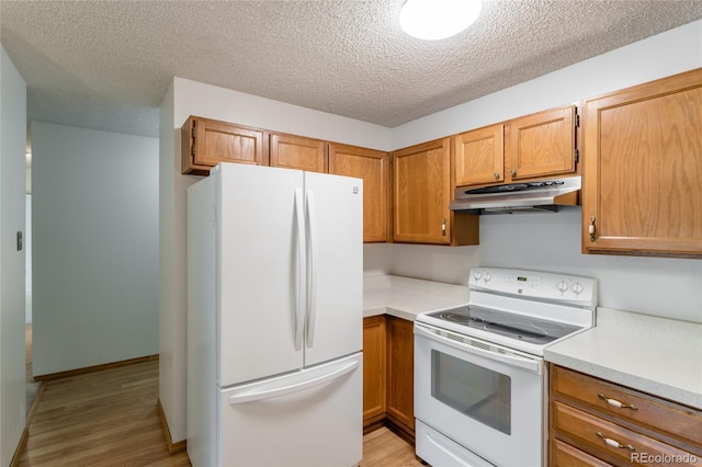 kitchen featuring white appliances, a textured ceiling, and light wood-type flooring