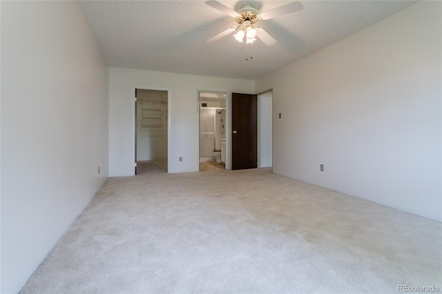 unfurnished bedroom with ensuite bathroom, ceiling fan, light colored carpet, a walk in closet, and a closet