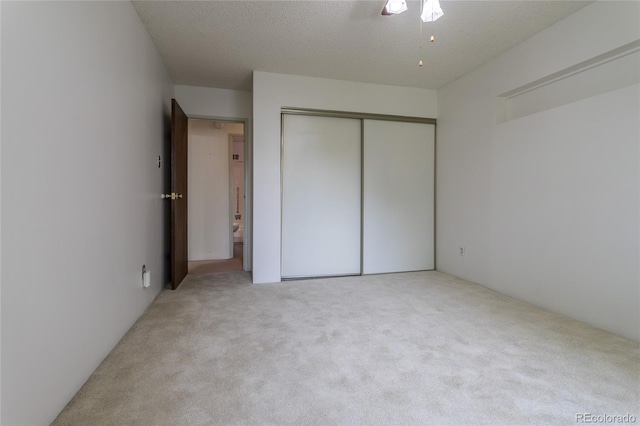 unfurnished bedroom featuring carpet floors, a textured ceiling, a closet, and ceiling fan