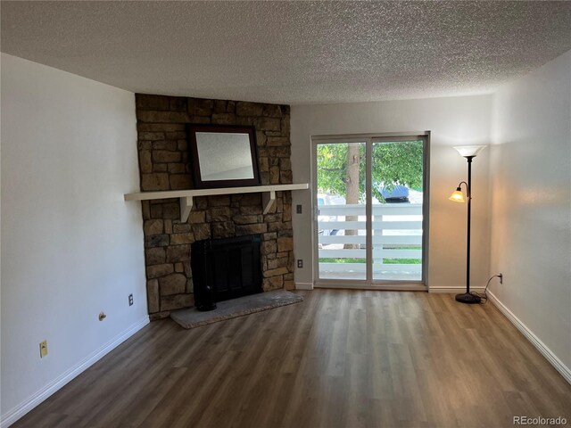 8555 Fairmount Dr Unit A108, Denver, CO 80247 - unfurnished living room with wood finished floors, a textured ceiling, a stone fireplace, and baseboards