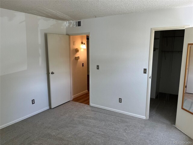 8555 Fairmount Dr Unit A108, Denver, CO 80247 - unfurnished bedroom with a spacious closet, carpet flooring, a textured ceiling, a closet, and baseboards