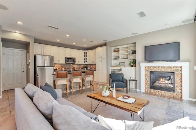 living room with a tile fireplace, sink, and light tile patterned floors