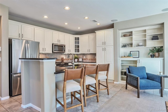 kitchen with appliances with stainless steel finishes, white cabinetry, sink, decorative backsplash, and light tile patterned floors