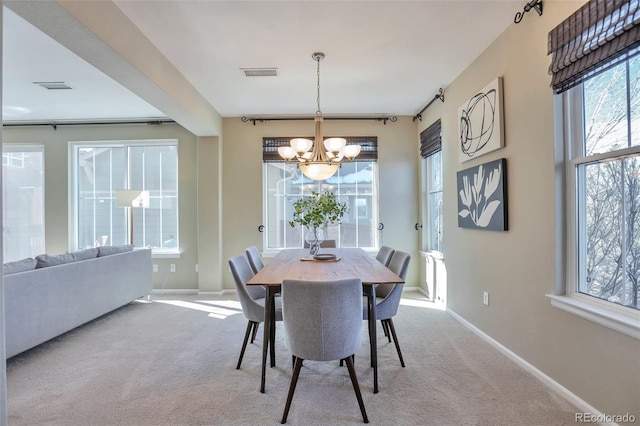 carpeted dining area with a chandelier