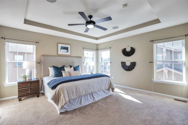 carpeted bedroom featuring ceiling fan and a tray ceiling