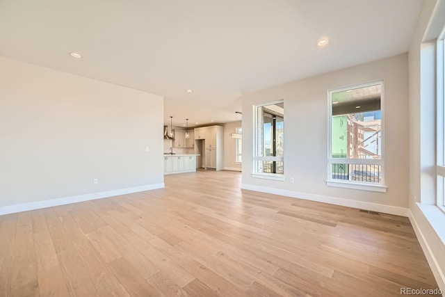 unfurnished living room featuring sink and light hardwood / wood-style floors