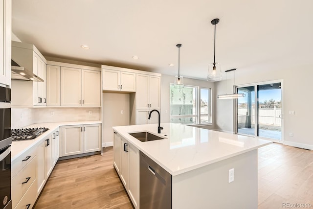 kitchen with pendant lighting, an island with sink, sink, white cabinets, and stainless steel appliances