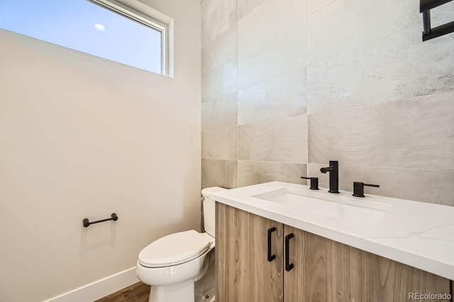 bathroom with vanity, tile walls, and toilet