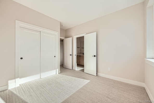 unfurnished bedroom featuring connected bathroom, light colored carpet, and a closet