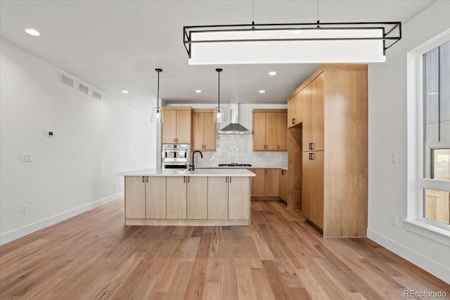5604 Grandville Ave, Longmont, CO 80503 - kitchen with wall chimney range hood, light countertops, light wood-type flooring, light brown cabinetry, and backsplash