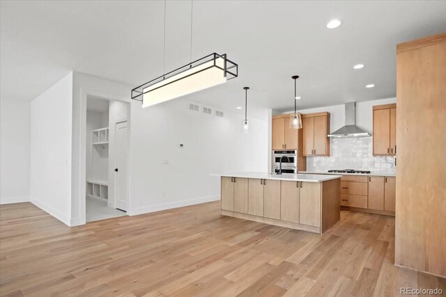 5604 Grandville Ave, Longmont, CO 80503 - kitchen with wall chimney exhaust hood, gas stovetop, light brown cabinetry, light wood finished floors, and backsplash