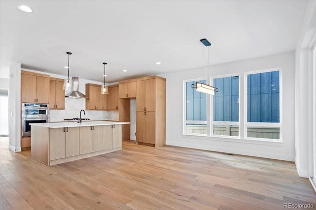 5604 Grandville Ave, Longmont, CO 80503 - kitchen with wall chimney range hood, recessed lighting, light countertops, light wood finished floors, and double oven
