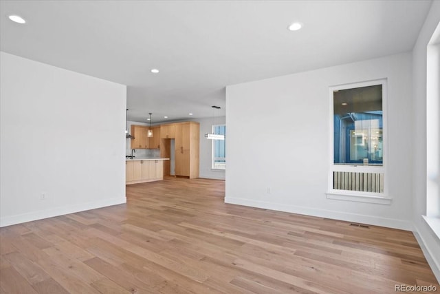 5604 Grandville Ave, Longmont, CO 80503 - unfurnished living room featuring a sink, light wood-style flooring, recessed lighting, and baseboards