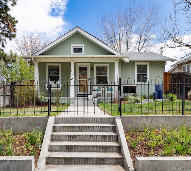bungalow-style house with a porch, a front lawn, stucco siding, and fence private yard