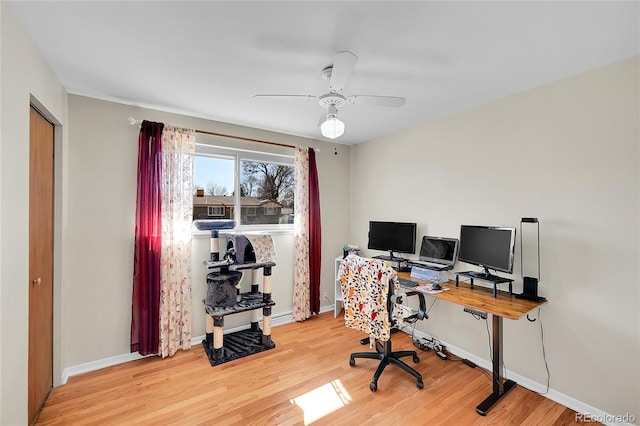 office area with a ceiling fan, light wood-type flooring, and baseboards