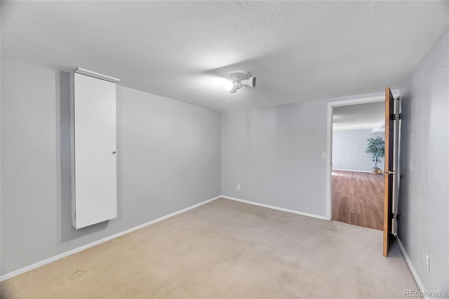 carpeted empty room with a textured ceiling and baseboards