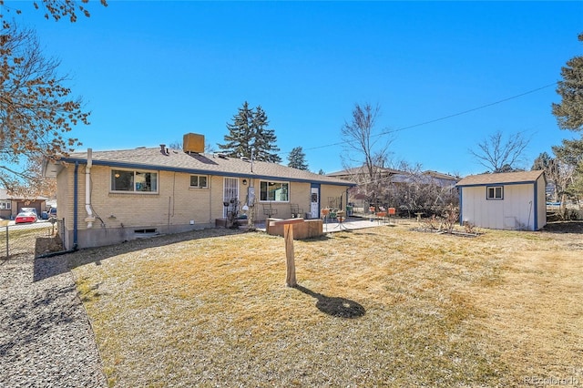 back of house with a storage shed, brick siding, an outdoor structure, a lawn, and a patio area