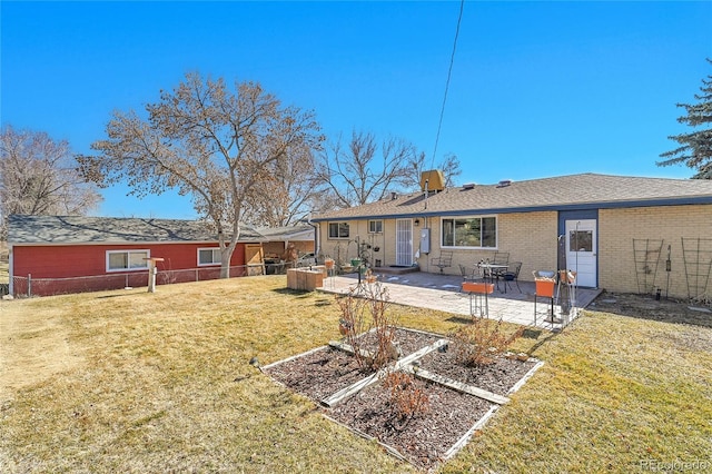 rear view of property with brick siding, a yard, a patio area, fence, and a garden