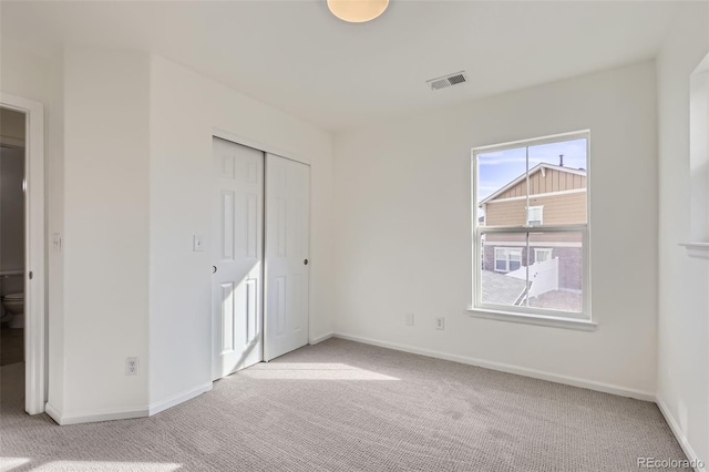 unfurnished bedroom with light carpet and a closet