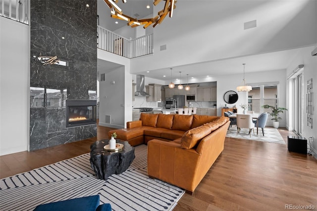 living room with a high ceiling, dark wood-type flooring, and a high end fireplace