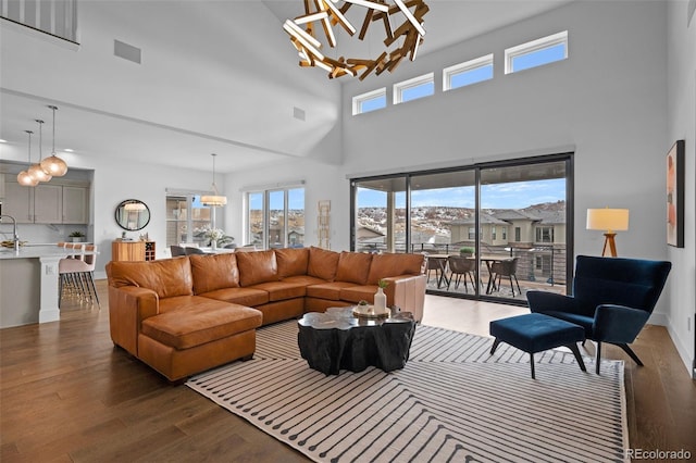 living room with dark hardwood / wood-style floors, a notable chandelier, and a towering ceiling