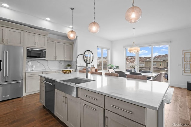 kitchen featuring pendant lighting, stainless steel appliances, and an island with sink