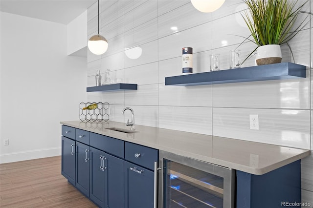 bar featuring sink, blue cabinetry, pendant lighting, and beverage cooler