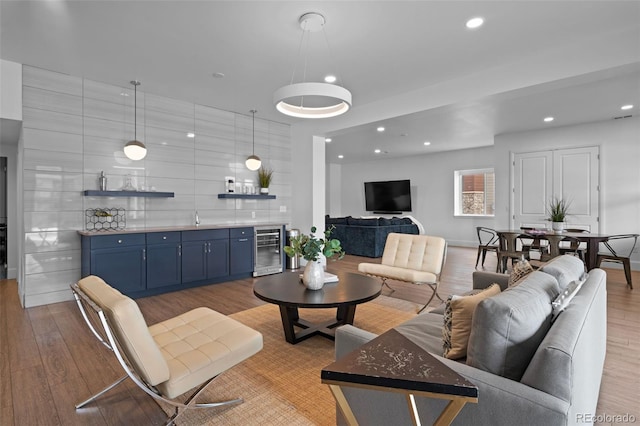 living room with indoor wet bar, beverage cooler, and light hardwood / wood-style floors