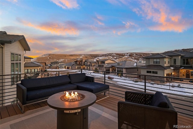 balcony at dusk featuring a mountain view and an outdoor living space with a fire pit