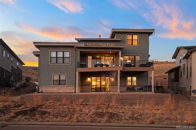 back house at dusk with a balcony