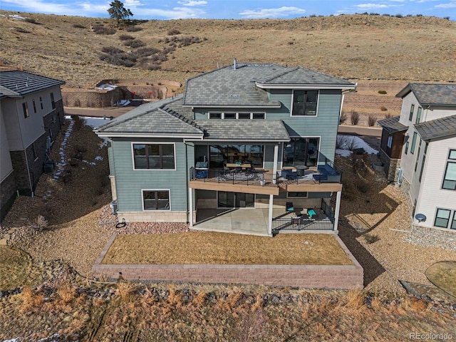 back of property with a yard, a patio area, and a balcony