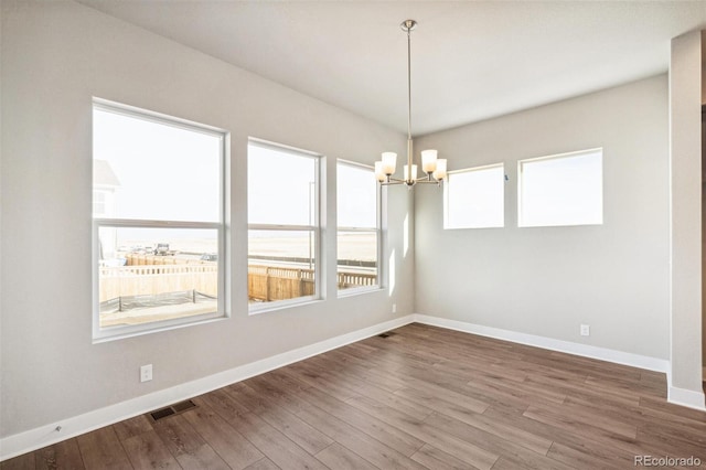 21295 E 61st Dr, Aurora, CO 80019 - spare room with visible vents, baseboards, wood finished floors, and a notable chandelier