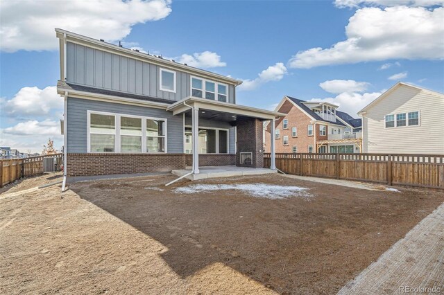 21295 E 61st Dr, Aurora, CO 80019 - back of property with a fenced backyard, central AC unit, brick siding, board and batten siding, and a patio