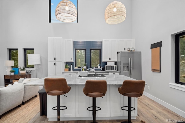 379 Rainbow Rd, Idaho Springs, CO 80452 - kitchen with a high ceiling, stainless steel appliances, white cabinets, a kitchen breakfast bar, and baseboards
