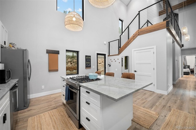 379 Rainbow Rd, Idaho Springs, CO 80452 - kitchen with a towering ceiling, stainless steel appliances, baseboards, white cabinetry, and light wood-style floors
