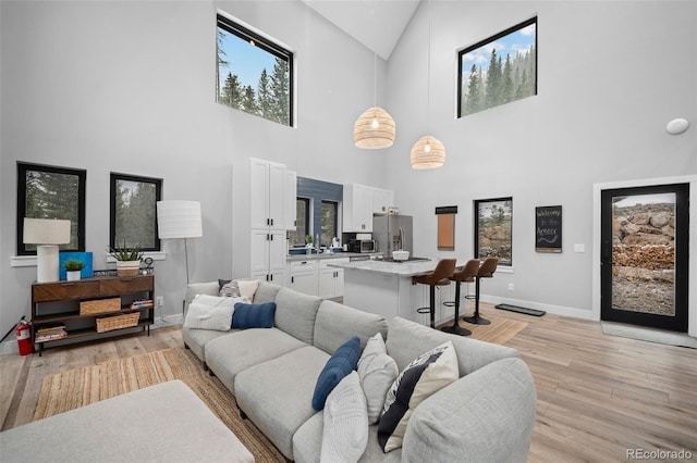 379 Rainbow Rd, Idaho Springs, CO 80452 - living area featuring light wood-type flooring, baseboards, high vaulted ceiling, and plenty of natural light