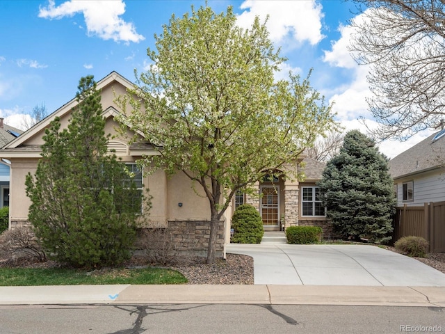 7158 W Belmont Dr, Littleton, CO 80123 - obstructed view of property featuring fence, stone siding, and stucco siding