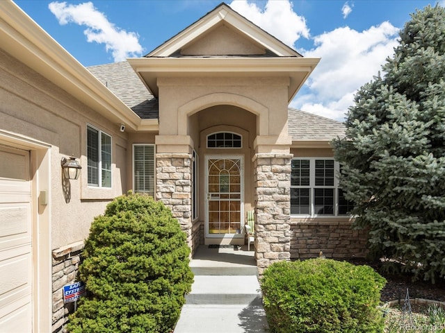 7158 W Belmont Dr, Littleton, CO 80123 - view of exterior entry featuring roof with shingles, stucco siding, and stone siding