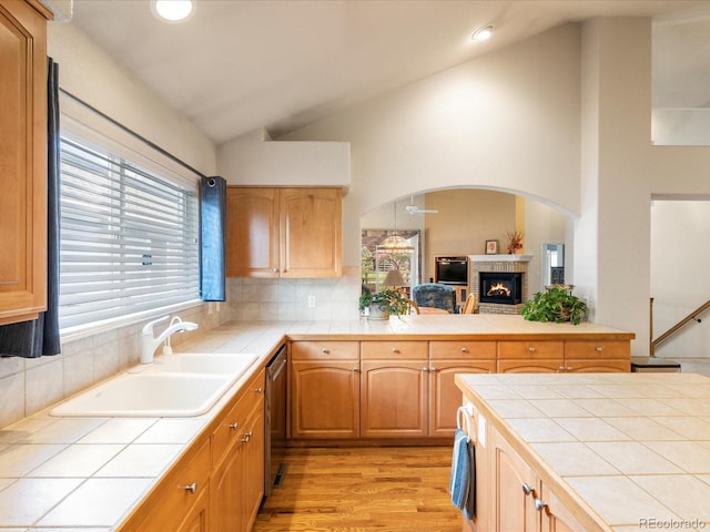 7158 W Belmont Dr, Littleton, CO 80123 - kitchen with dishwasher, light wood-style floors, tile countertops, decorative backsplash, and vaulted ceiling