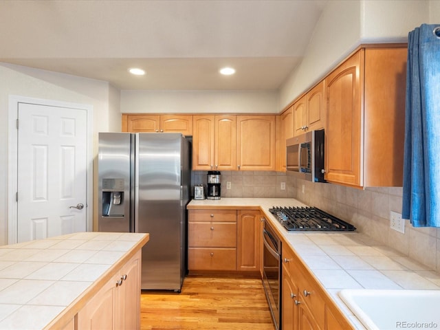 7158 W Belmont Dr, Littleton, CO 80123 - kitchen featuring light wood-style floors, stainless steel appliances, tasteful backsplash, and tile countertops