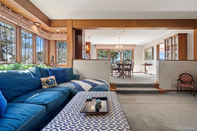 carpeted living area with baseboards and an inviting chandelier