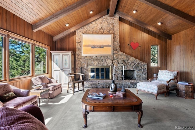 living area with wood walls, carpet, beam ceiling, and a stone fireplace