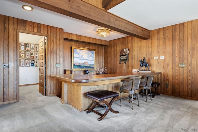 bar featuring wooden walls, baseboards, carpet flooring, a bar, and beam ceiling